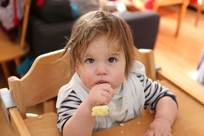 Close-up of cute baby girl with messy face looking away while sitting on chair at home