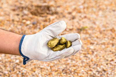 Close-up of hand holding golden stones