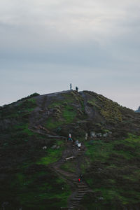 Rear view of man walking on mountain against sky