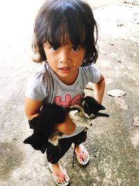 Portrait of girl holding kittens while standing on field