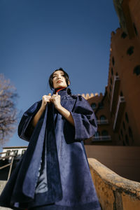 Young woman wearing coat looking away during sunny day