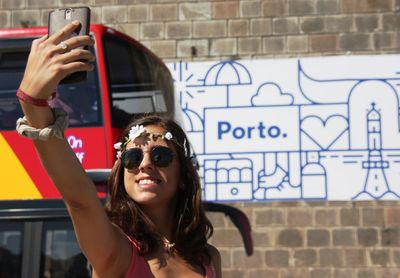 Young woman clicking selfie through mobile phone by bus