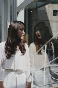 Close-up of young woman standing against wall