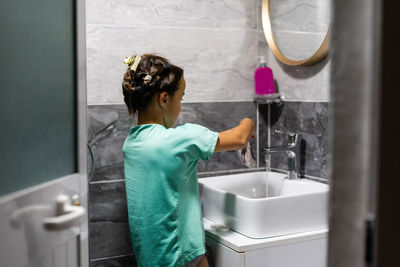 Side view of woman washing hands in bathroom