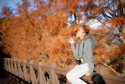 Man sitting by railing during autumn