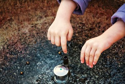 Cropped hands of child playing with container outdoors