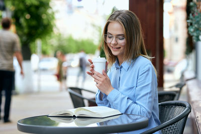 Young businesswoman using mobile phone while sitting in cafe