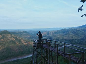 People looking at mountain range against sky