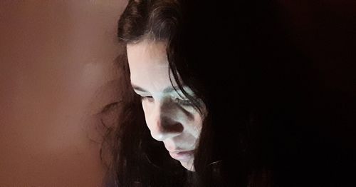 Close-up portrait of young woman against black background