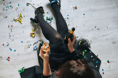 Young happy woman forty years plus size body positive in black dress drinks champagne at home 