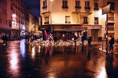 People on wet illuminated city at night