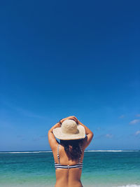 Rear view of woman wearing hat against sea against sky