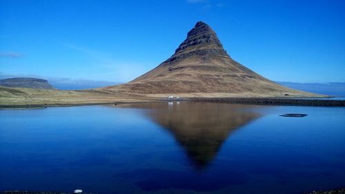 Scenic view of kirkjufell and blue lake against sky