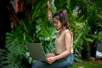 Young woman using mobile phone while sitting outdoors