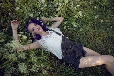 Portrait of a teenage girl with purple hair and an earring in her nose lie in the grass in nature