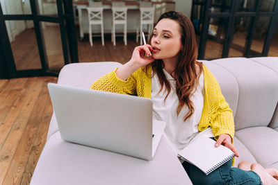 Young woman using phone while sitting on table