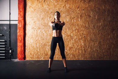 Full length portrait of woman standing against wall