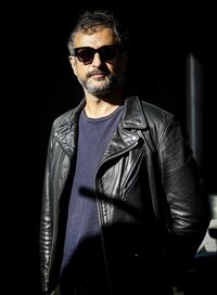 Young man wearing sunglasses standing against black background