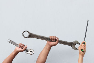 Close-up of hand holding chain against white background