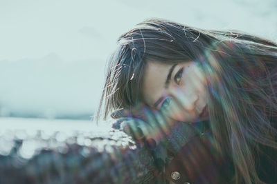 Portrait of mid adult woman leaning on retaining wall against sky during sunny day