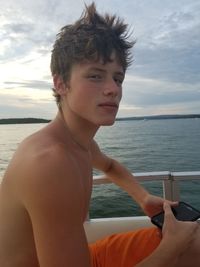 Portrait of young man looking at sea against sky