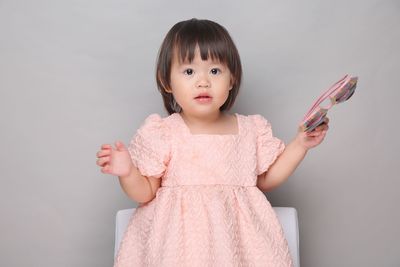 Portrait of cute girl standing against wall