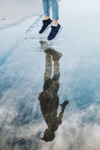 Low section of man jumping on puddle