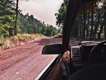 Dirt road seen through car against sky