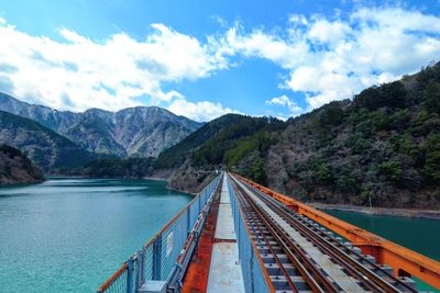Bridge over river amidst mountains against sky