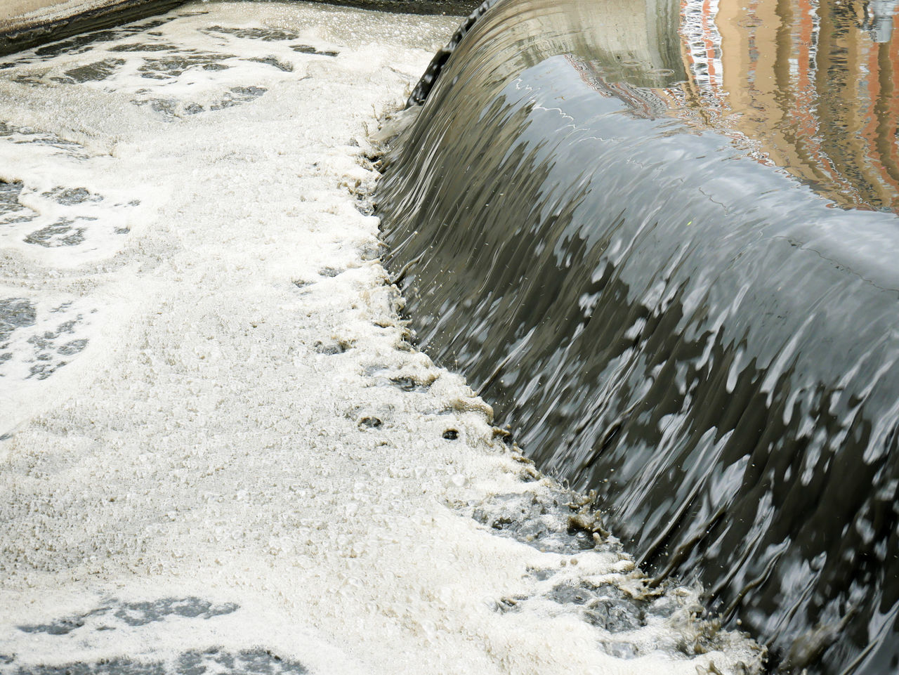 HIGH ANGLE VIEW OF WATER FLOWING OVER SEA