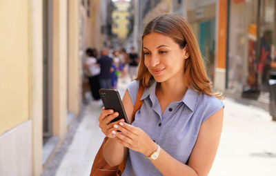 Happy young woman in city street using a mobile phone