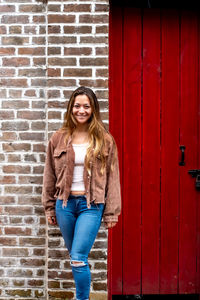 Portrait of a smiling young woman against wall