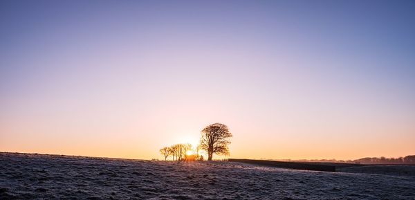 Scenic view of landscape against clear sky at sunset