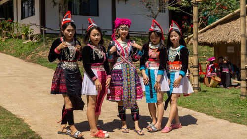 Full length portrait of smiling women standing against wall