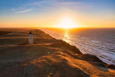 Rubjerg knude fyr lighthouse in sunset from drone