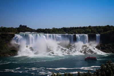 View of waterfall against blue sky