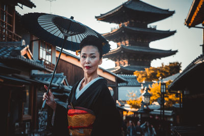 Portrait of woman standing against buildings