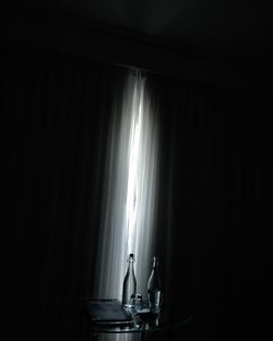 Illuminated lamp on table by window at home