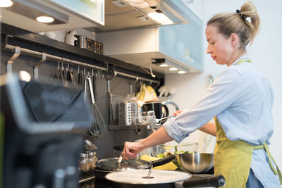 Side view of woman preparing food in kitchen