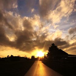 Road amidst buildings against sky during sunset