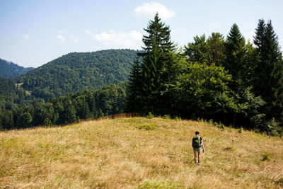 Man walking on dirt road amidst trees and mountains