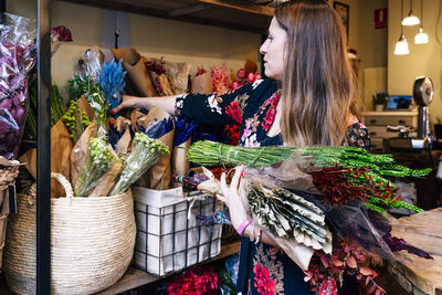 Professional female florist arranging flower bouquet while working in shop