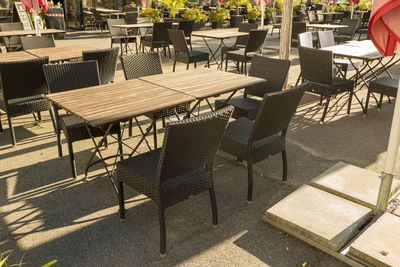 Empty chairs and tables at sidewalk cafe amidst buildings