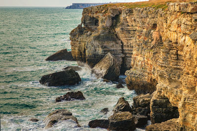 Rock formation on sea shore against sky