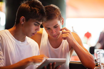 Friends using digital tablet while sitting in cafe