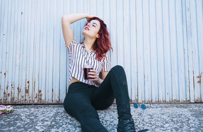 Portrait of young woman standing against wall