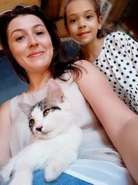 Portrait of mother and daughter with cat at home