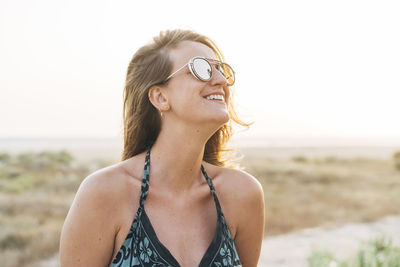 Young woman wearing sunglasses on beach against sky
