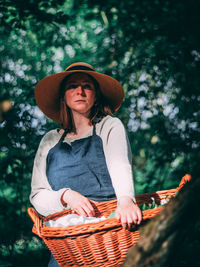 Woman wearing hat standing against trees