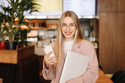 Portrait of businesswoman entrepreneur with glasses looking at the camera in a public place in cafe